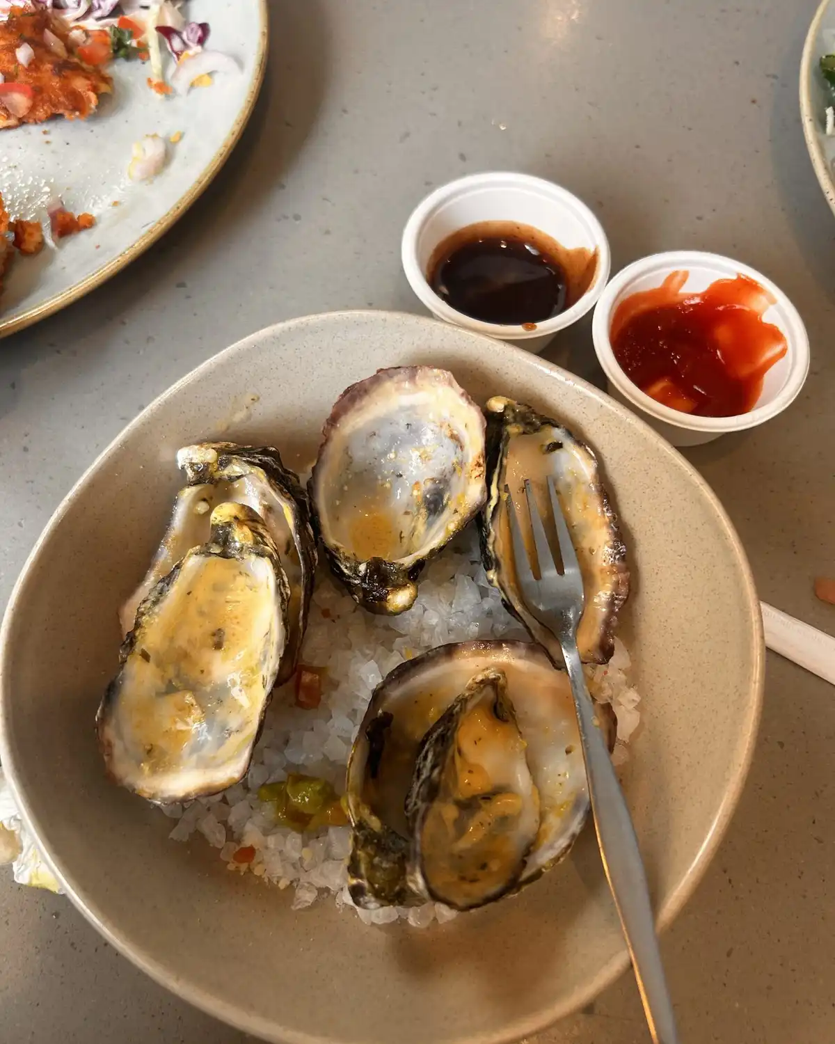 Oysters on a bed of salt with two small cups of sauce