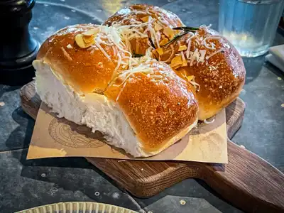 Glazed milk buns topped with grated cheese on a wooden board